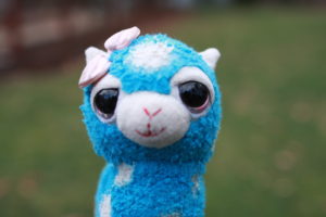 Wooly is a female, blue alpaca with white spots, and a pink bow